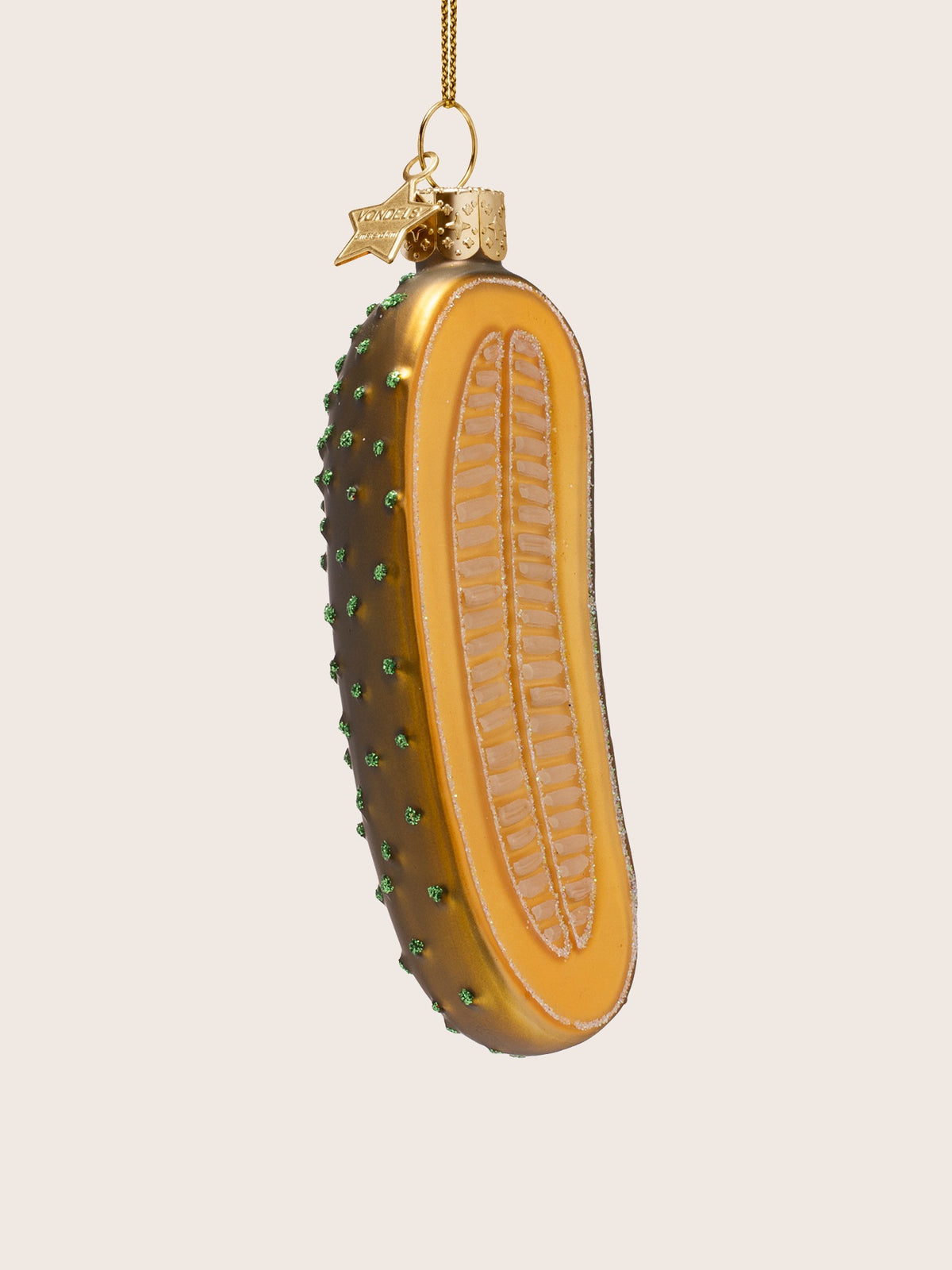 Three-quarter view of the pickle slice ornament showing the dark green textured skin with glitter bumps