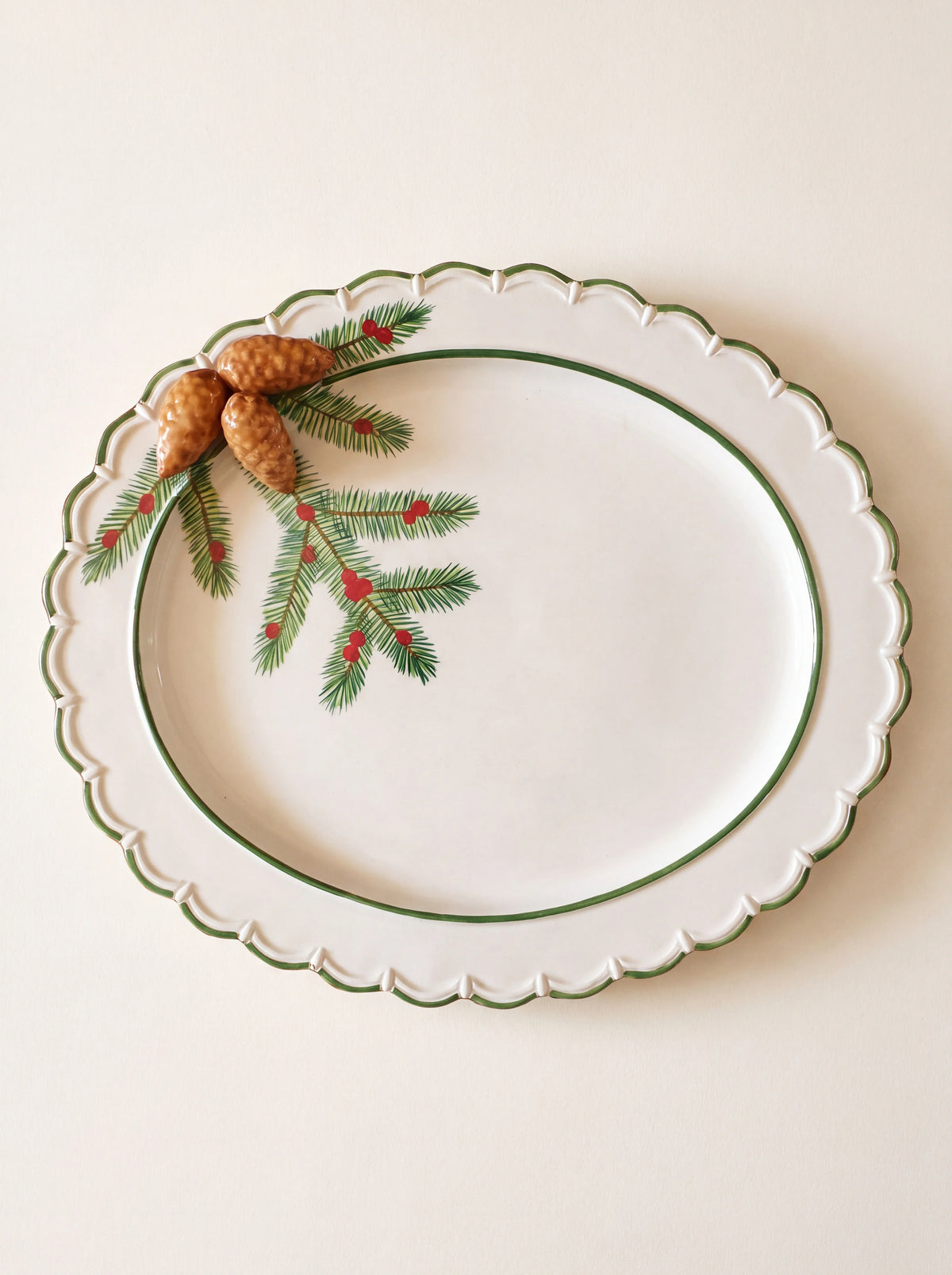 Oval white ceramic tray with a scalloped green rim, painted pine branch with berries and three raised pine cones