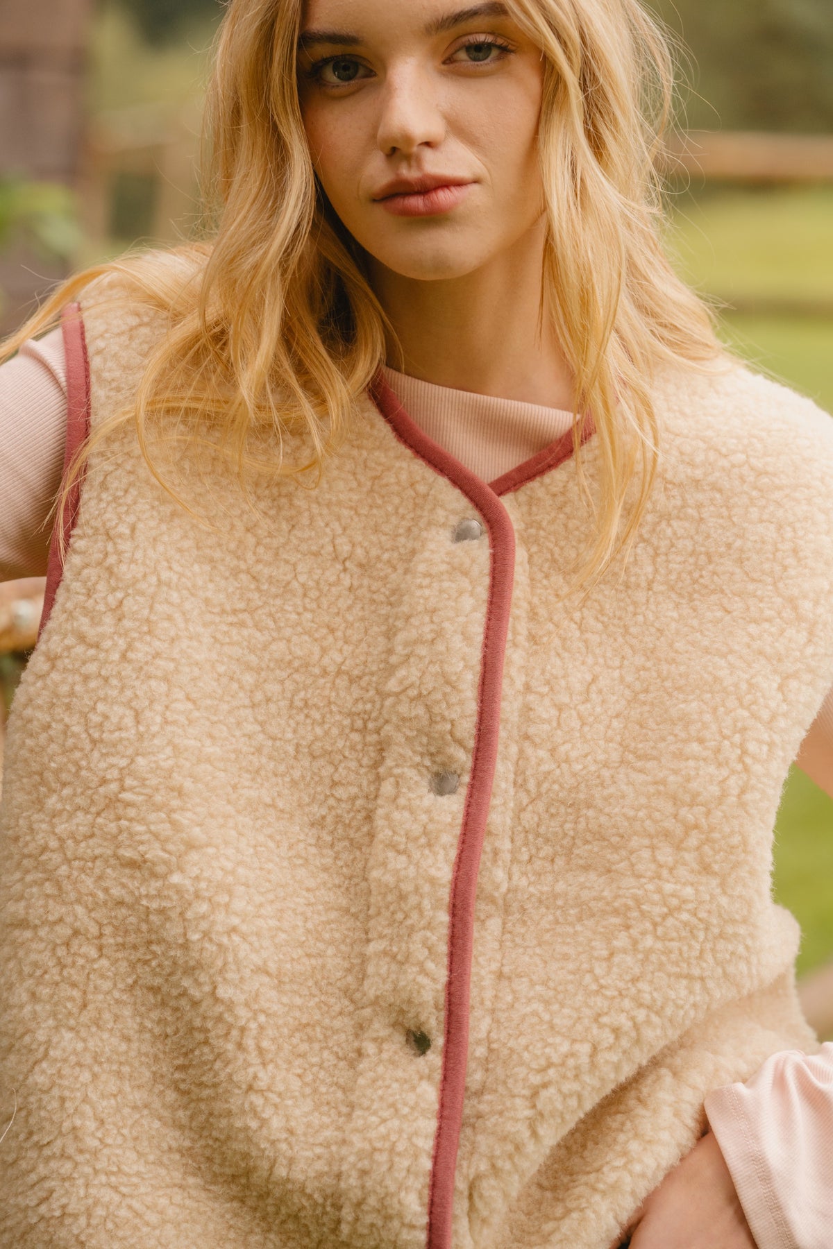 Light beige wool pile vest with snap-button fastening and contrasting pink edge trim