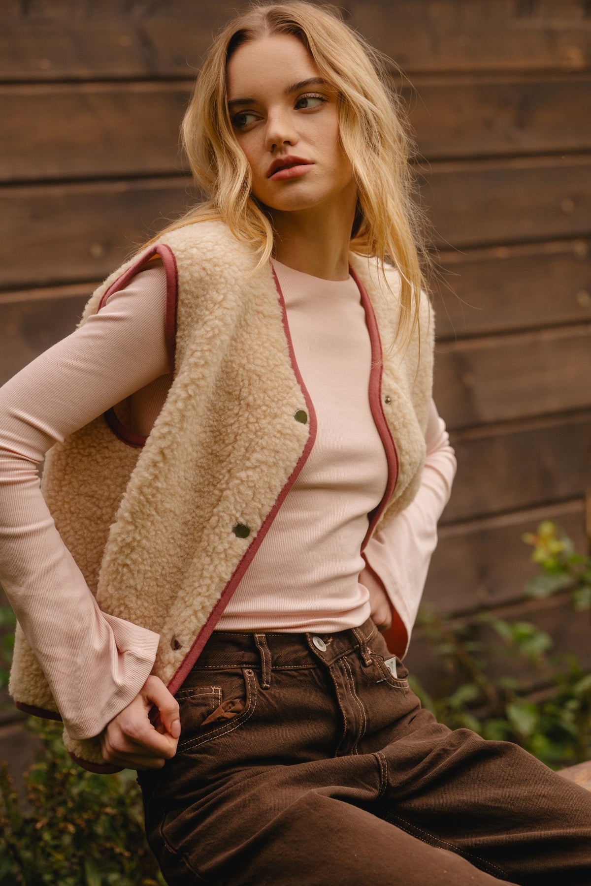 Light beige wool vest worn unfastened, showing the inner snap fasteners and armholes