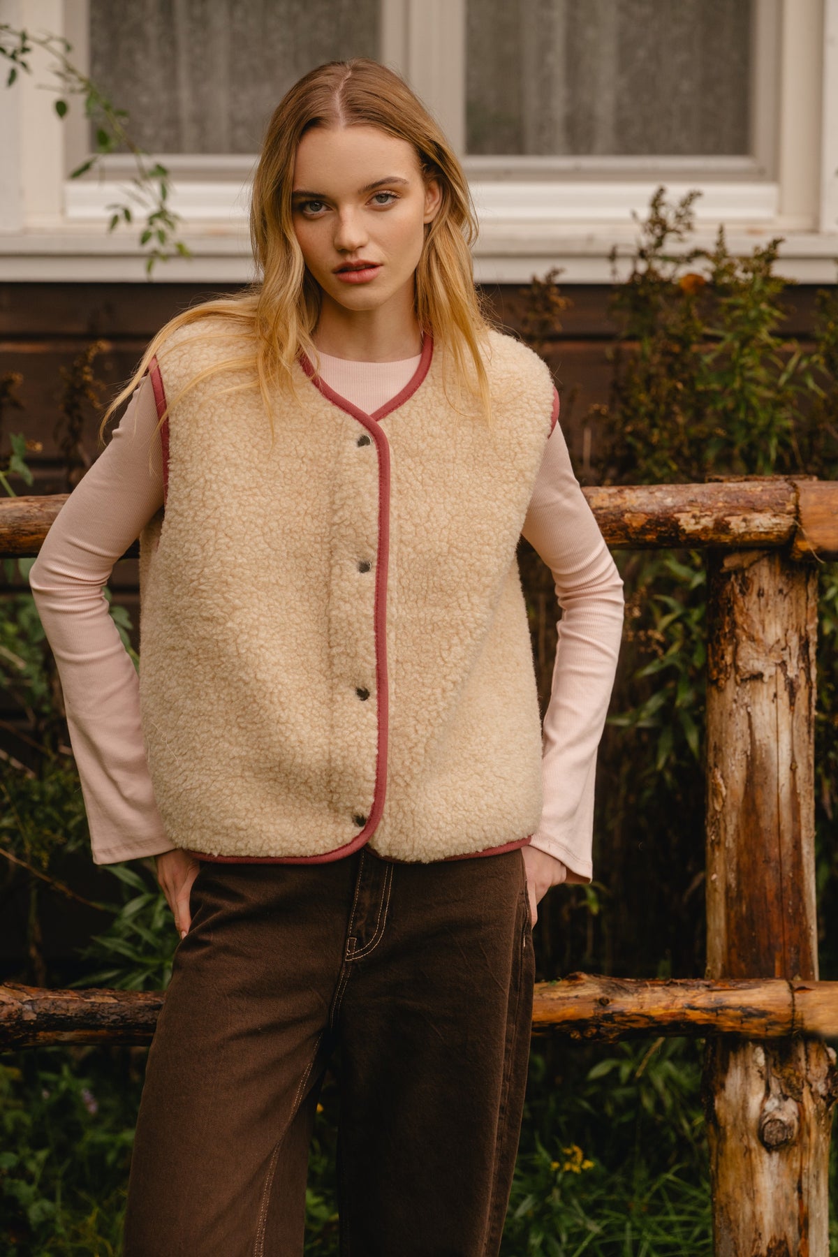 Front view of the fastened light beige wool vest, showing the boxy shape and waist length