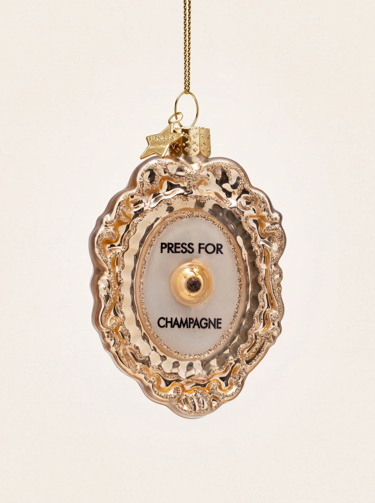 Scalloped gold glass Christmas ornament with glitter trim and black lettering reading PRESS FOR CHAMPAGNE