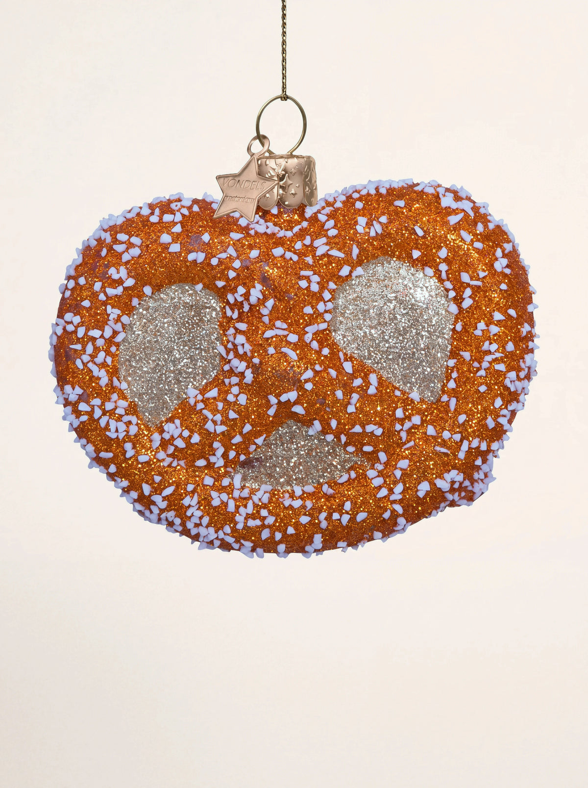 Pretzel-shaped glass ornament covered in amber and gold glitter with white textured salt flakes