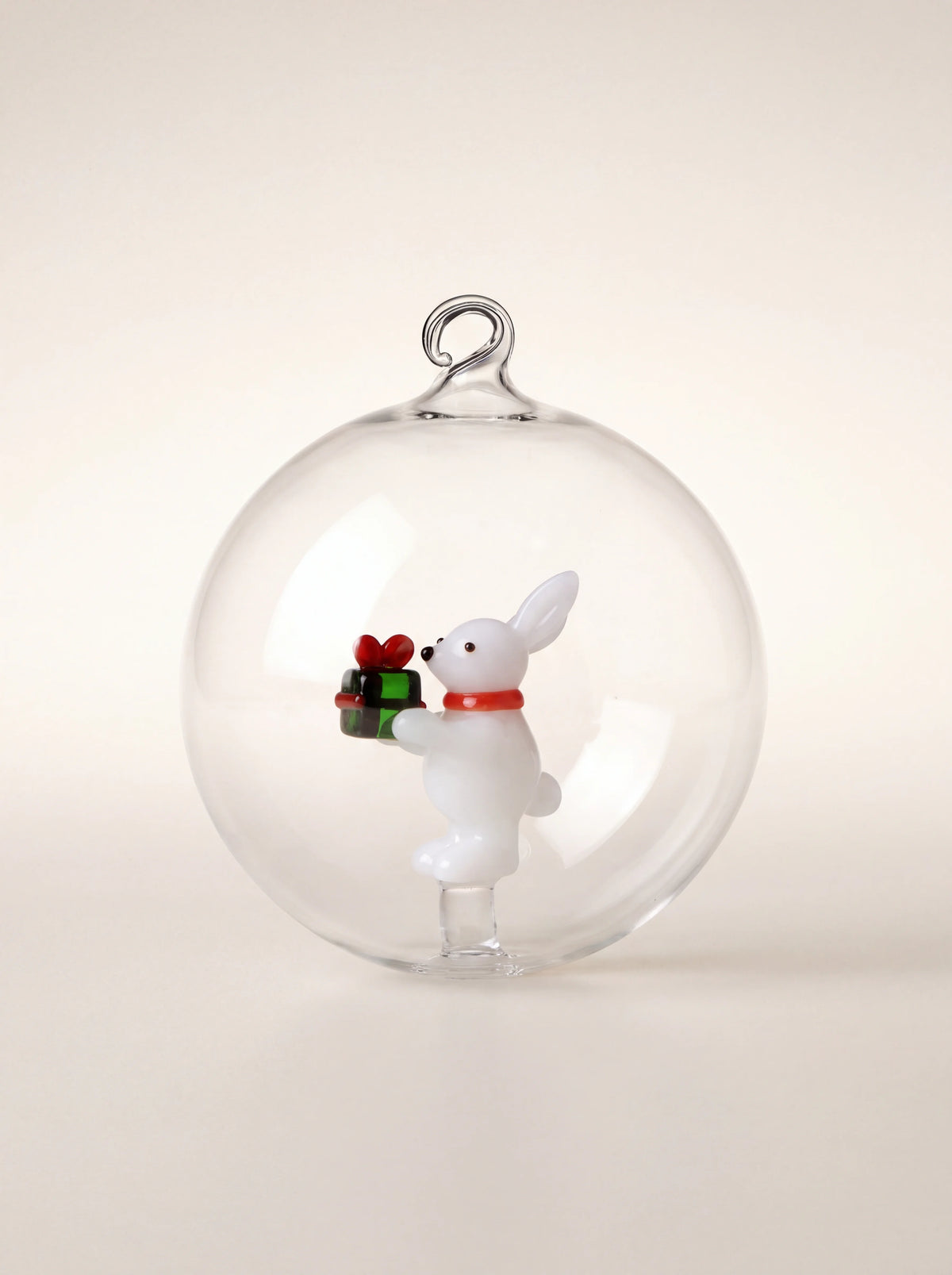 Clear borosilicate glass bauble with an internal white rabbit figurine holding a green gift box
