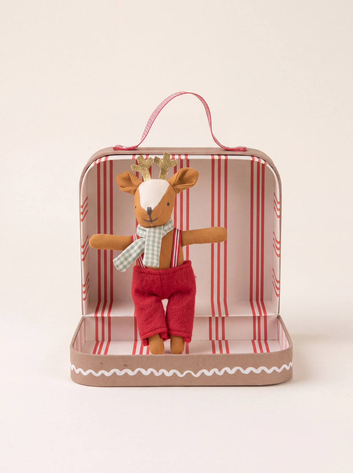 Reindeer doll with gold antlers and red dungarees inside an open red-striped cardboard suitcase