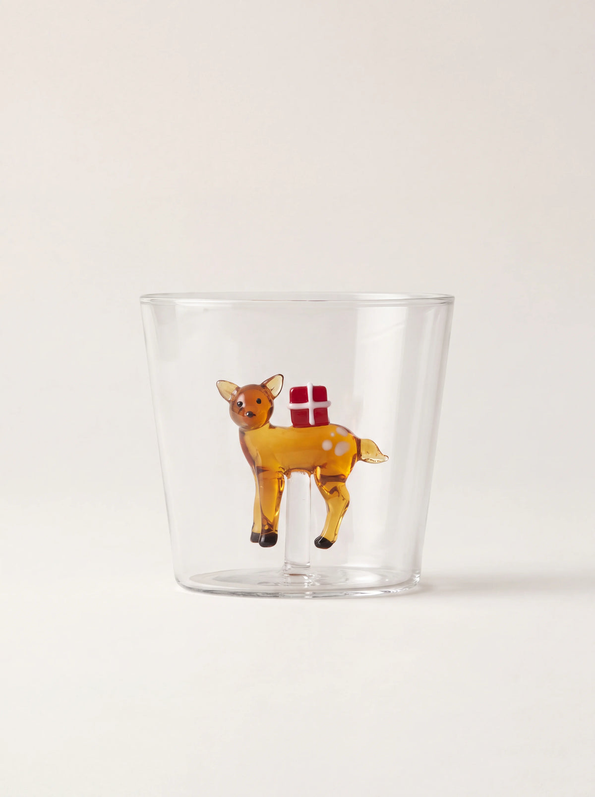 Clear borosilicate glass tumbler with an amber reindeer figurine carrying a red gift inside