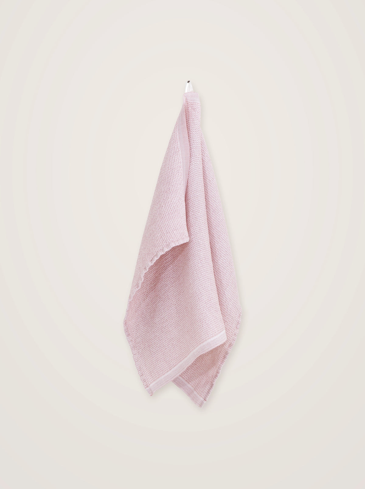 Relief-weave rose towel draped from an integrated hanging loop, showing its textured weave and smooth edges