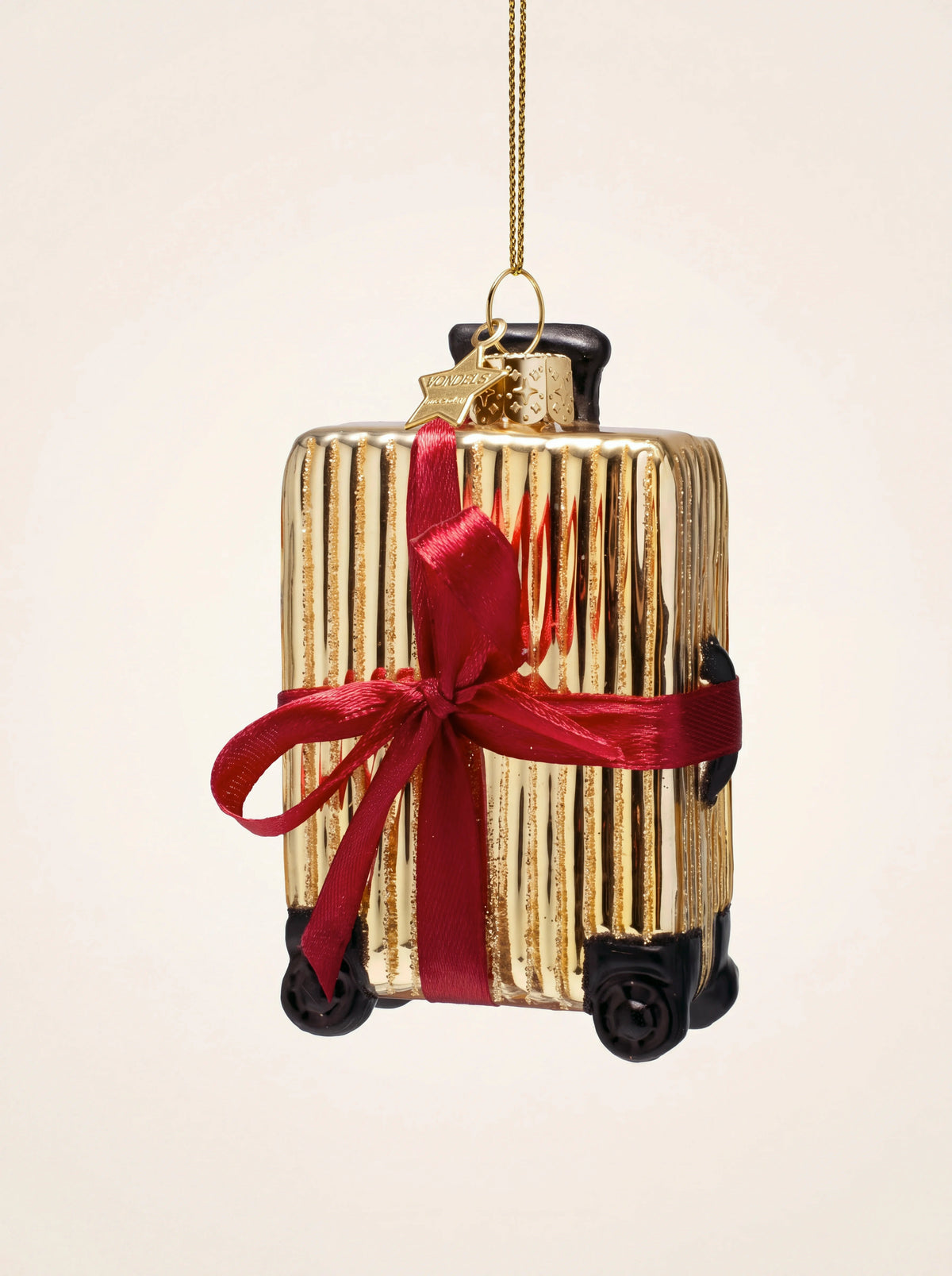 Gold ribbed glass suitcase ornament tied with a red ribbon bow, with black wheels and a hanging loop