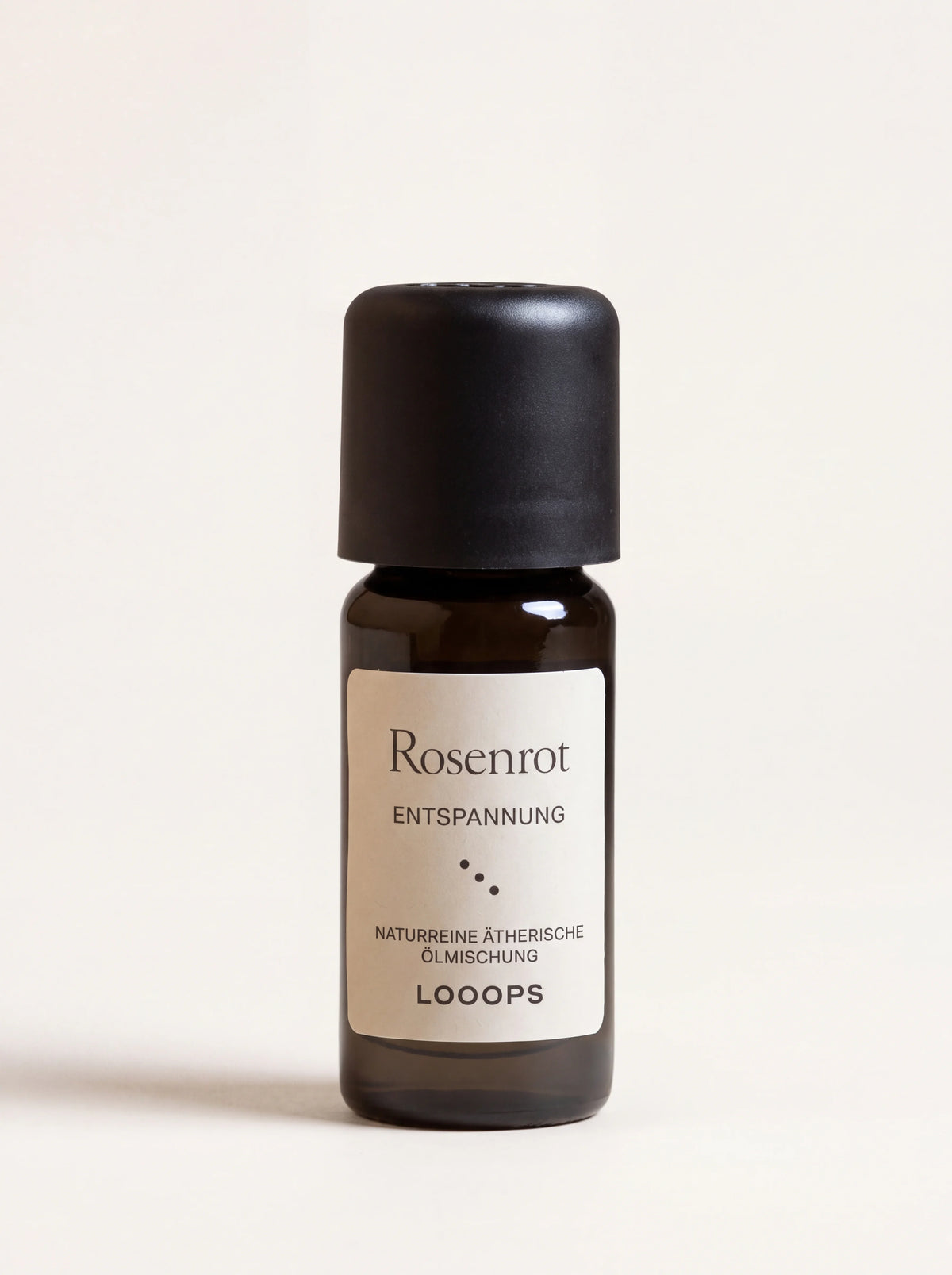 Rosenrot essential oil in an amber glass bottle with a black cap and label reading Rosenrot Entspannung
