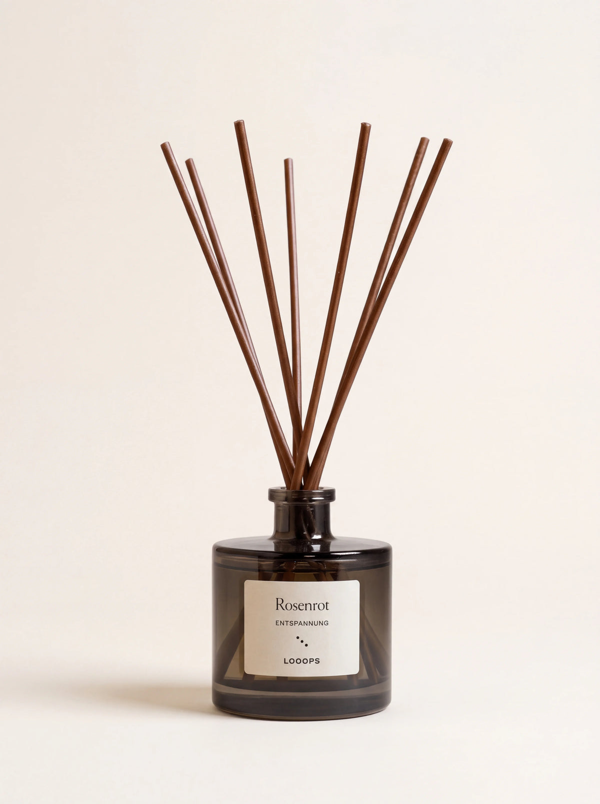 Smoked glass reed diffuser with brown paper reeds and label reading Rosenrot Entspannung