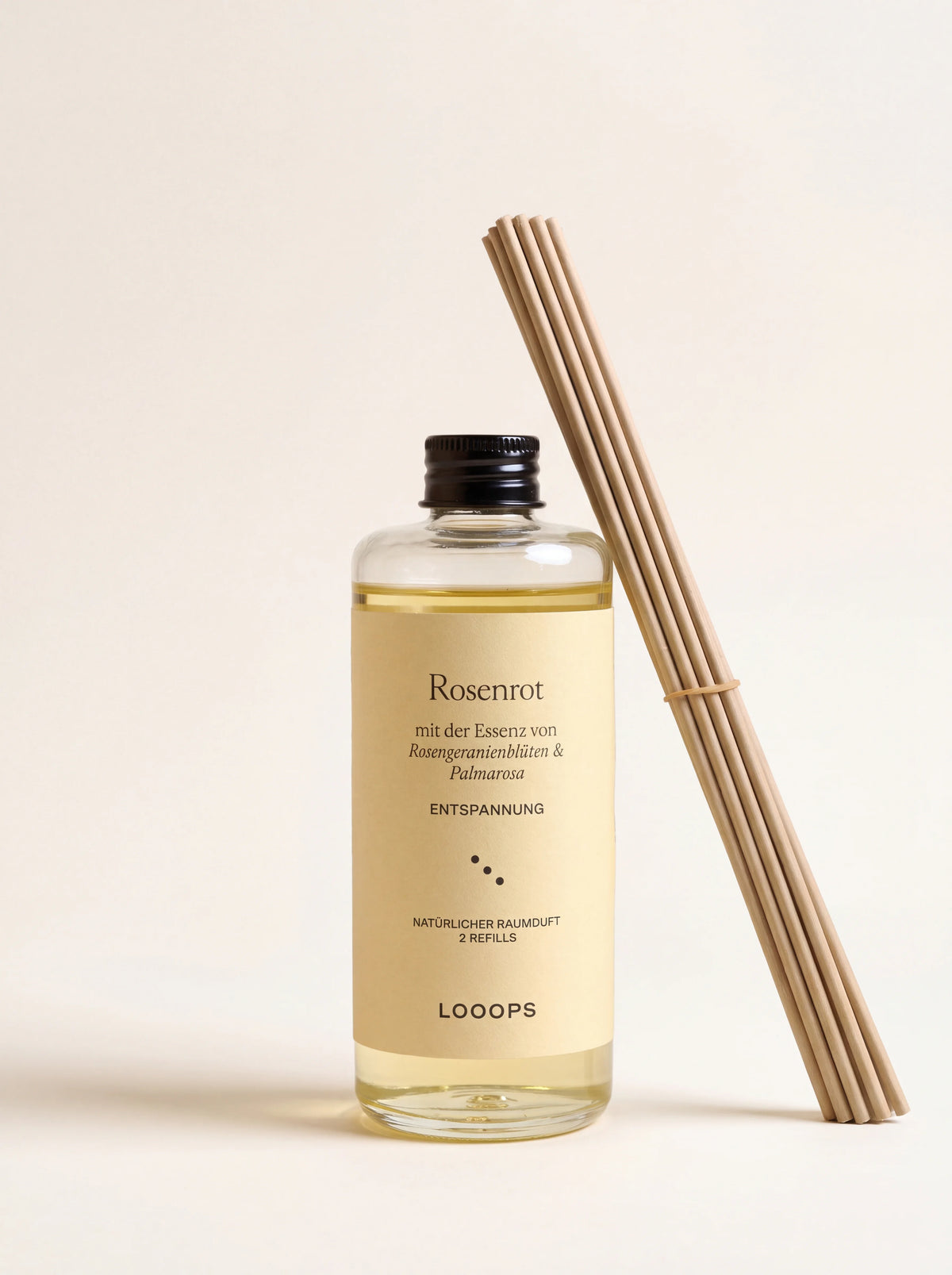 Reed diffuser refill in a clear glass bottle with a black screw cap, alongside a bundle of paper reeds