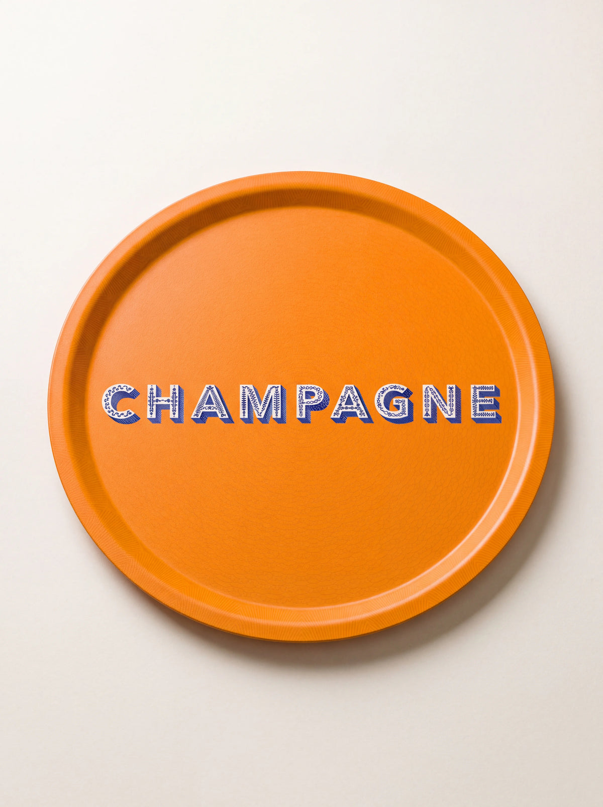 Round orange birch wood tray with raised rim and patterned CHAMPAGNE lettering across the centre