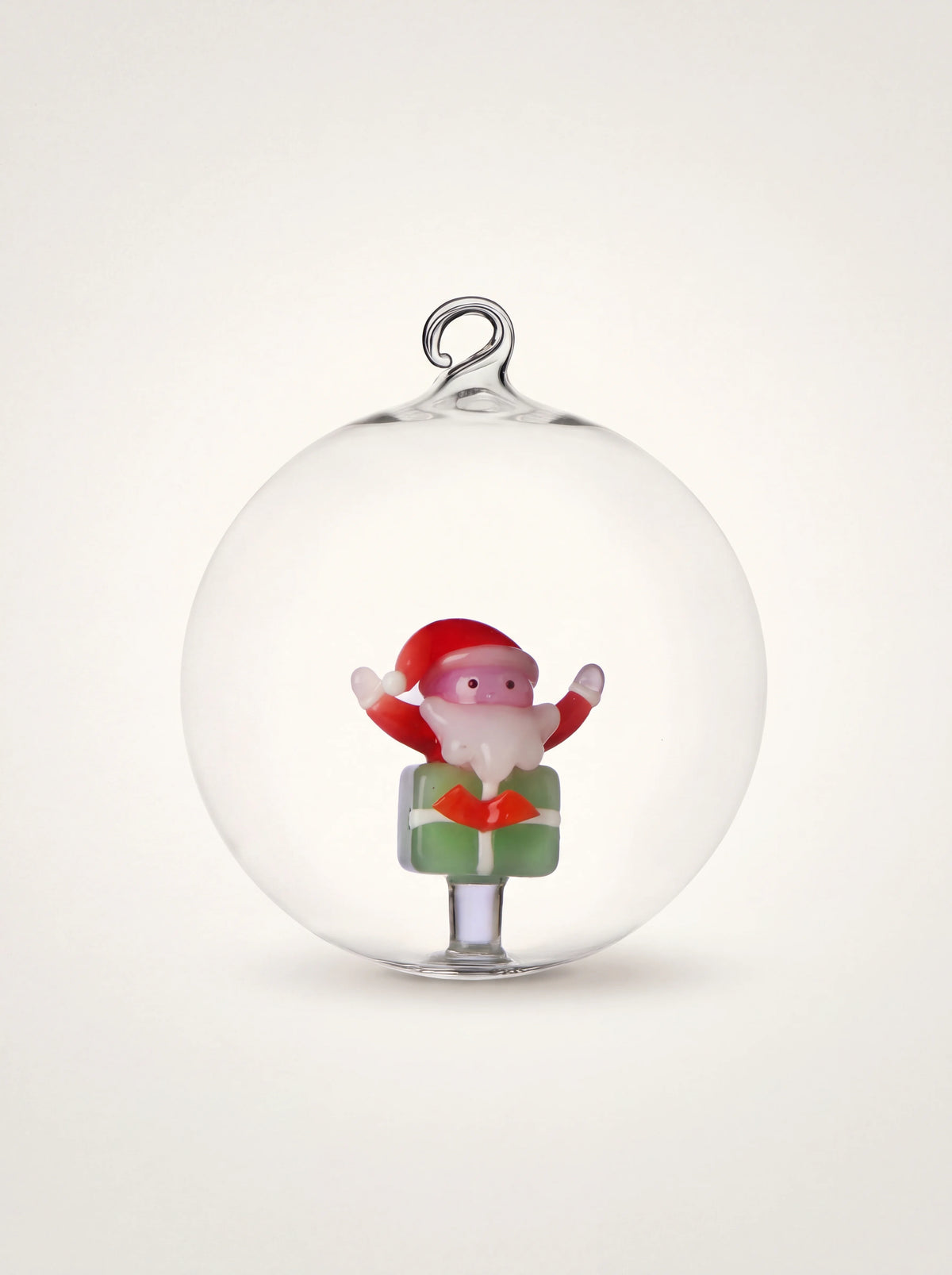 Clear borosilicate glass bauble with an internal Santa Claus figurine sitting on a green gift box