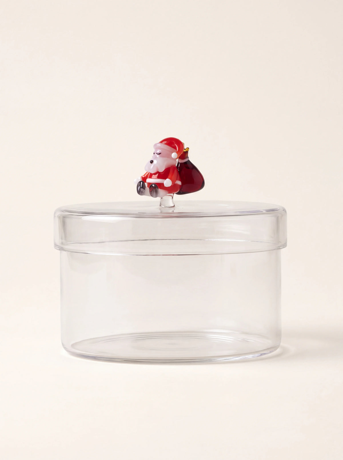 Cylindrical clear glass box topped with a Santa Claus figurine holding a red sack