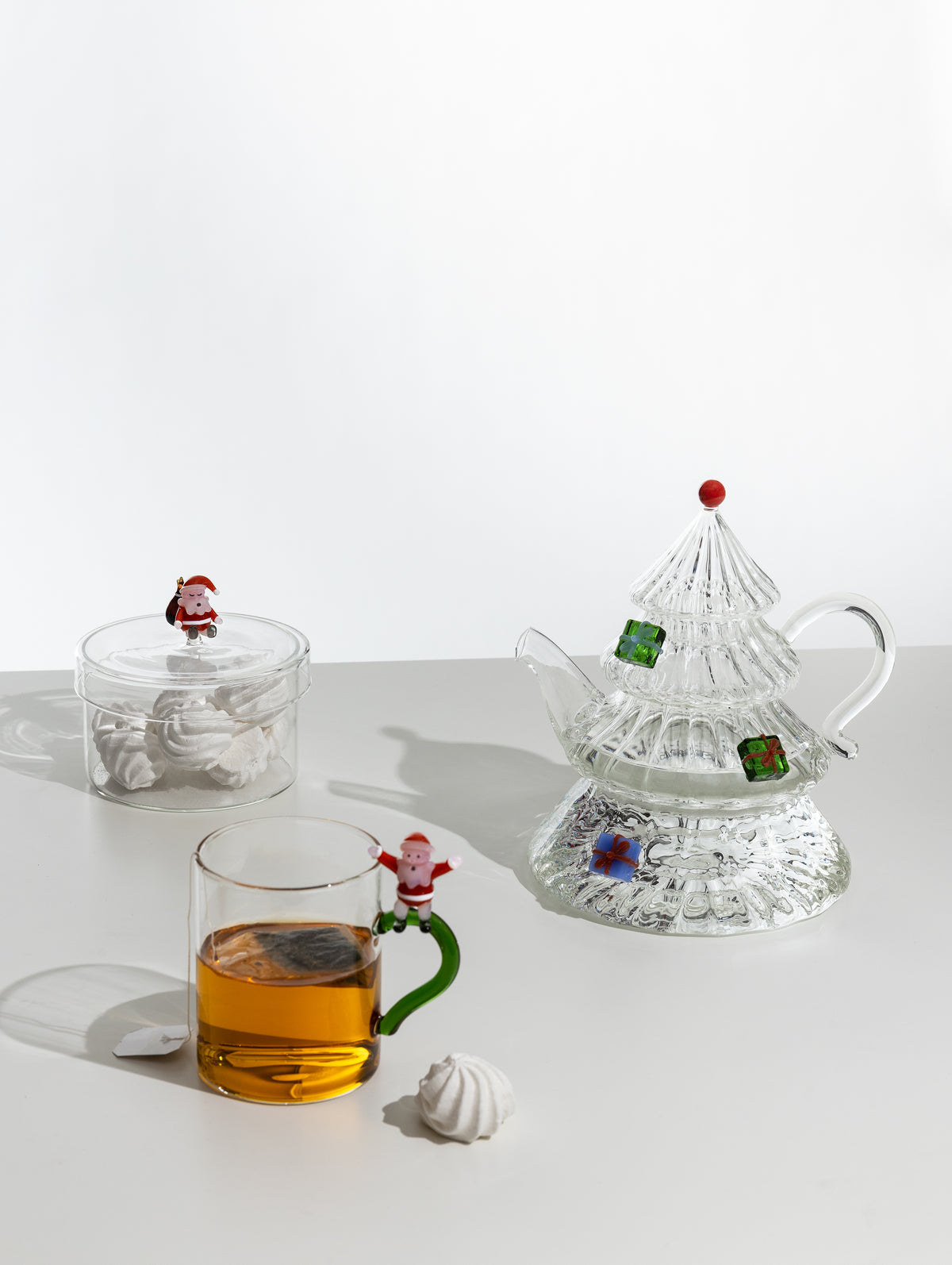 Glass box filled with meringues, shown on a table beside a festive glass teapot and mug