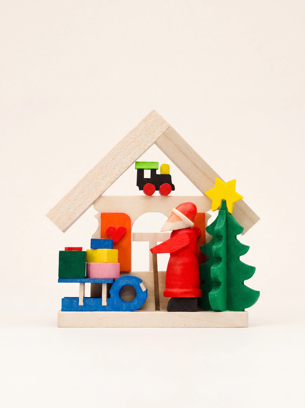 Wooden house Christmas ornament featuring Santa, a green tree, a blue sledge with gifts and a toy train