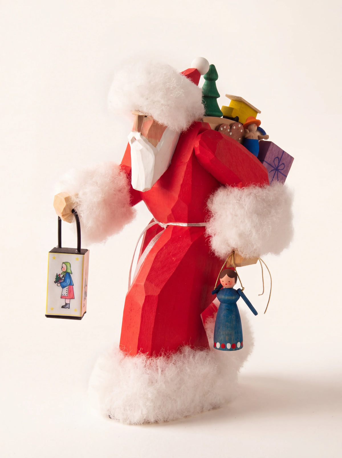 Carved wooden Santa figure in red with plush white trim, holding a lantern and carrying toys on his back