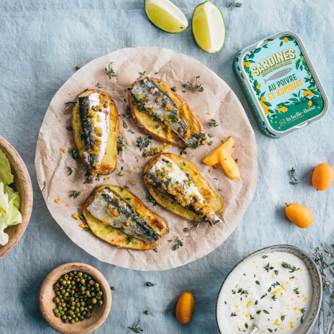 Sardines served over roasted potato slices alongside fresh kumquats, green peppercorns and dip