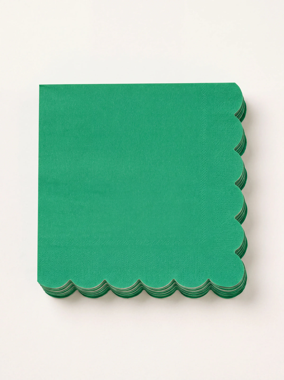 Stack of square fir green paper napkins with scalloped edges along two sides