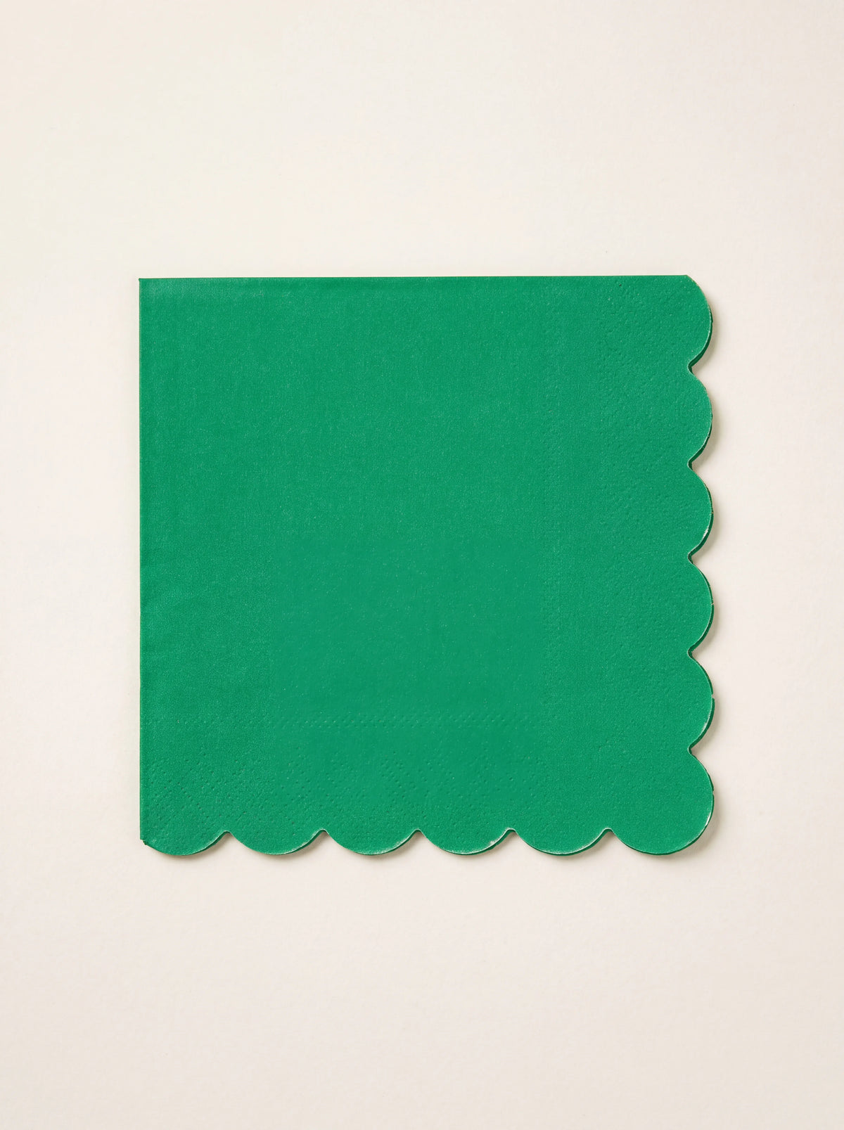 Folded square paper napkin in fir tree green with scalloped edges