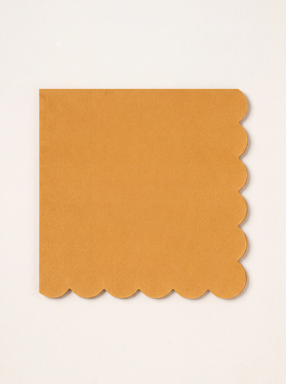 Square folded paper napkin in warm harvest yellow with scalloped edges