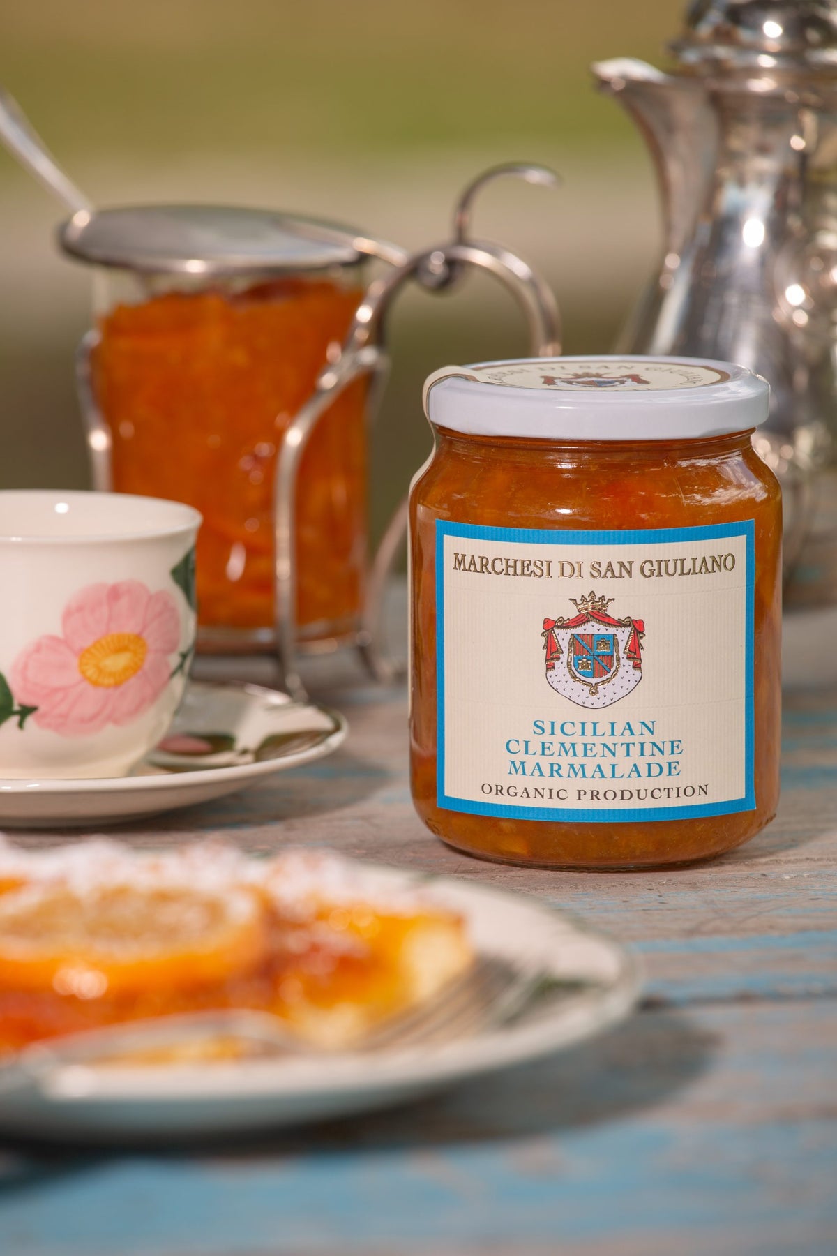 Sicilian clementine marmalade jar set on a breakfast table beside a teacup and citrus tart