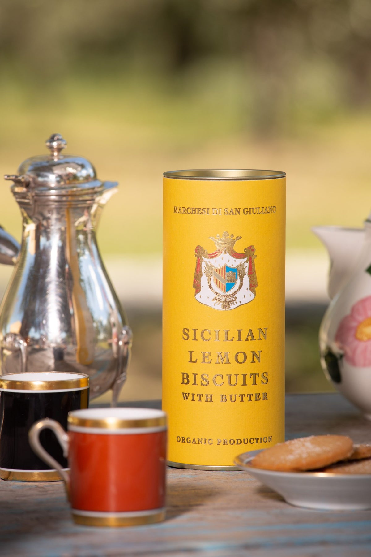 Sicilian lemon biscuit tin shown beside small cups, a silver pot, and round biscuits on a saucer
