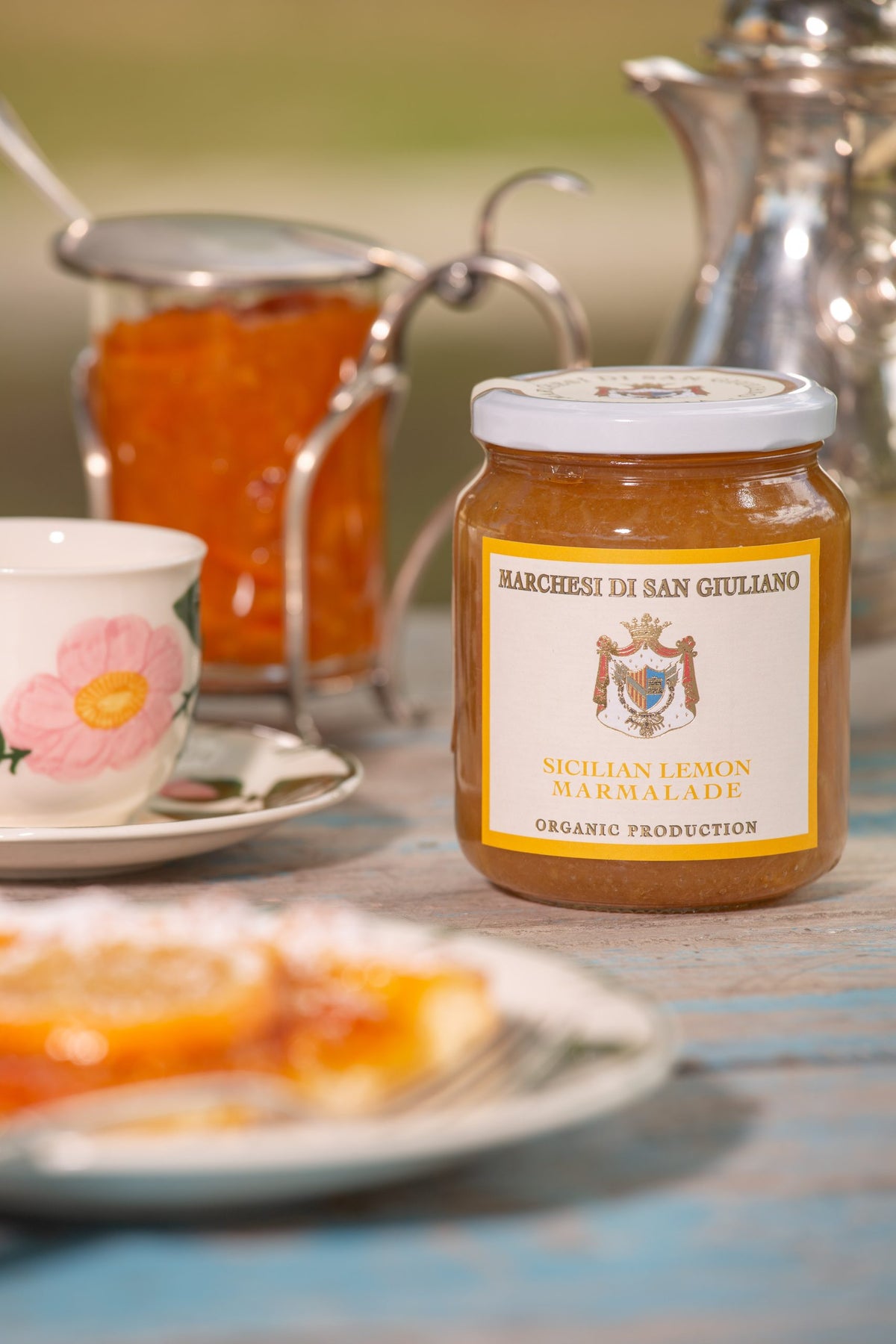 Sicilian lemon marmalade jar served on a table setting beside a floral teacup and tart