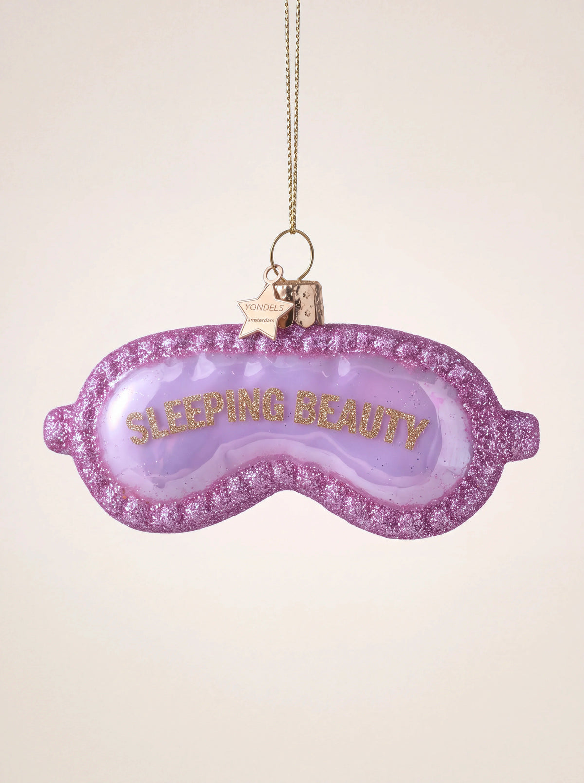 Pink glass sleep mask ornament with gold glitter lettering reading SLEEPING BEAUTY and glitter trim