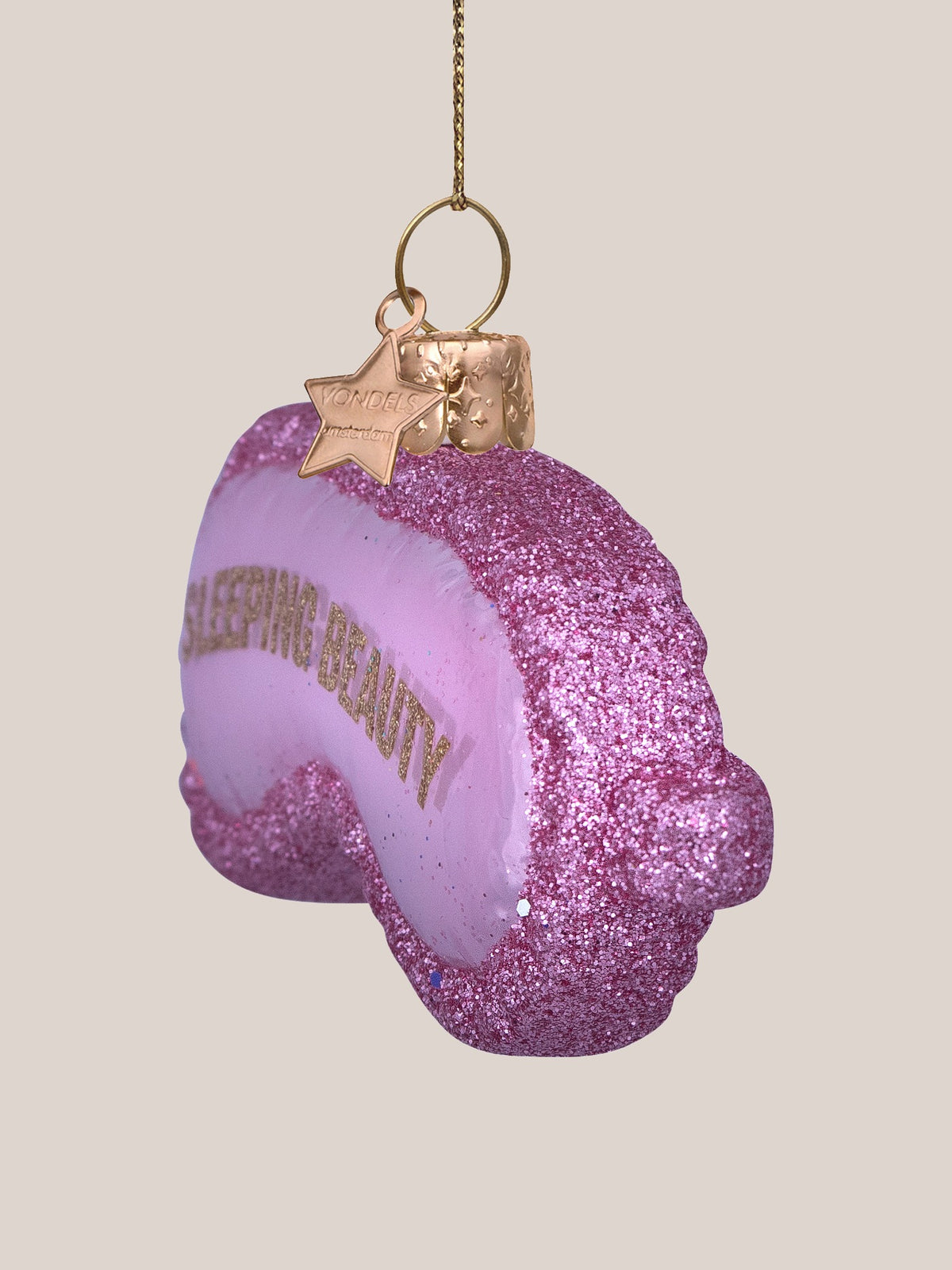 Glass sleep mask ornament in side profile, showing its curved depth and thick glitter edge