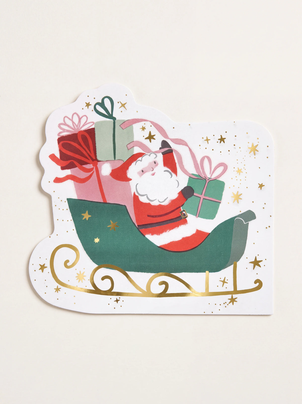 Die-cut paper napkin shaped like Santa in a green sleigh packed with gifts, featuring gold-foil details