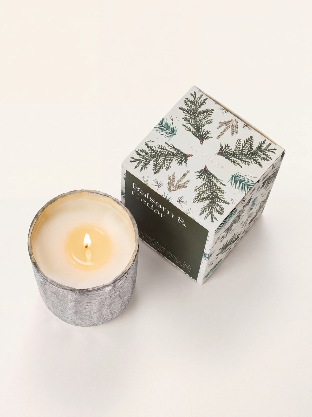 Top view of the lit candle showing the single burning wick and pool of wax beside the illustrated box
