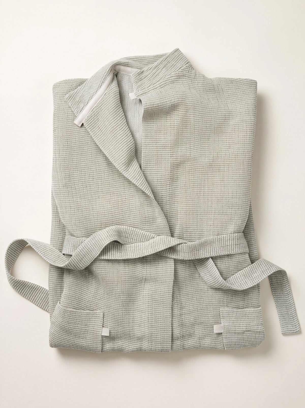 Waffle-weave bathrobe in white-olive, neatly folded with a shawl collar and matching tie belt