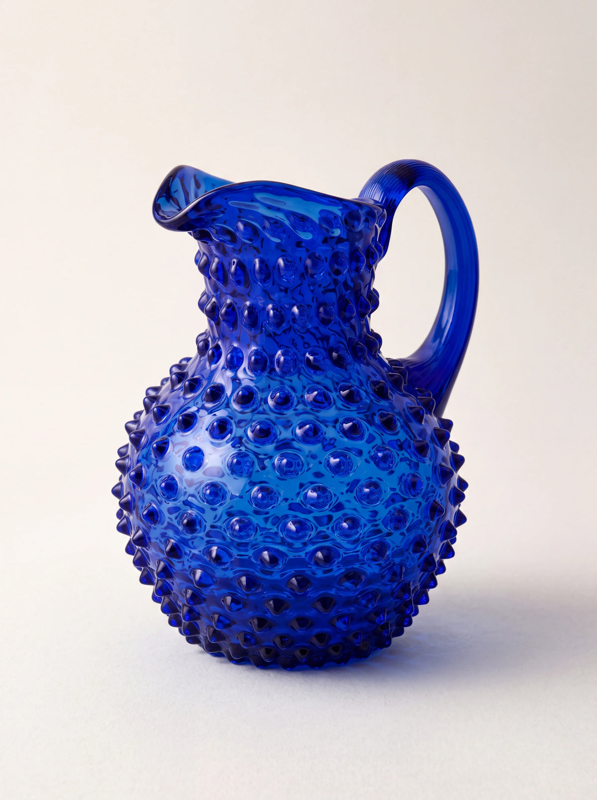 Dark blue hobnail glass jug with a rounded body, flared spout and curved handle