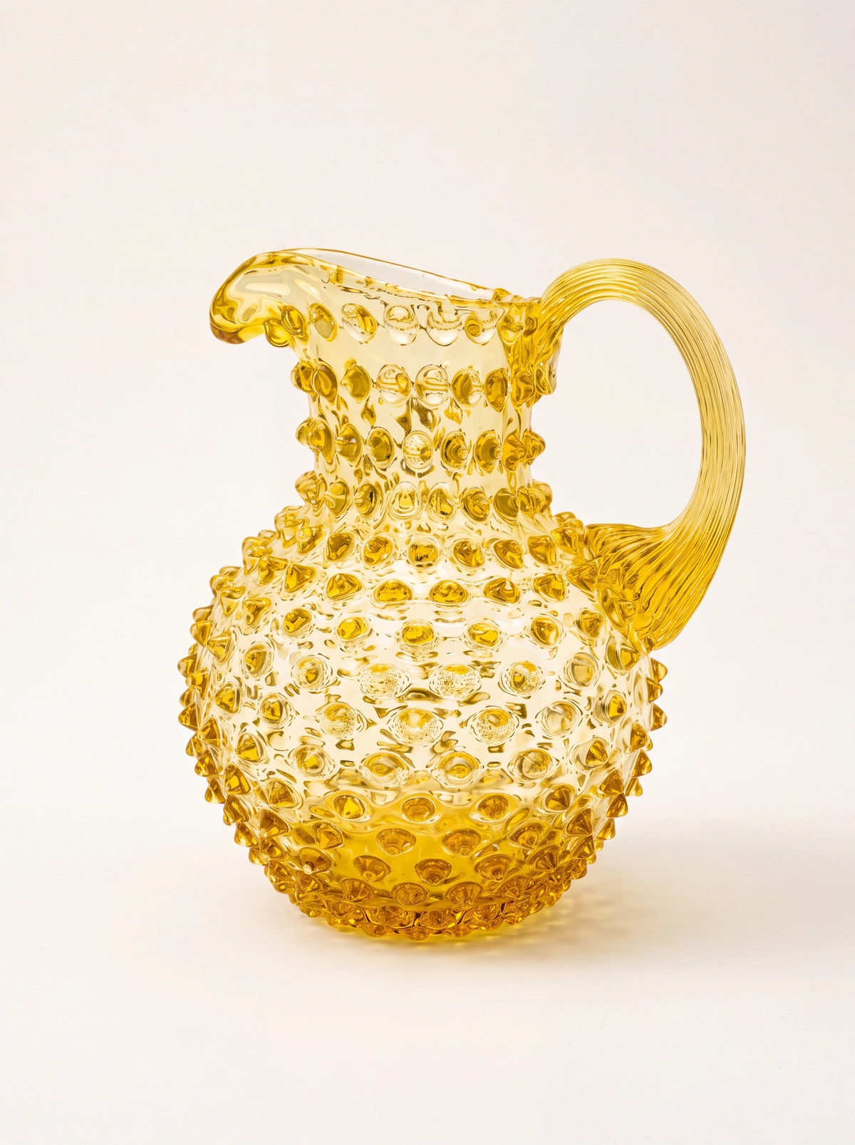Yellow hobnail glass jug with a bulbous body, pinched spout and arched ribbed handle
