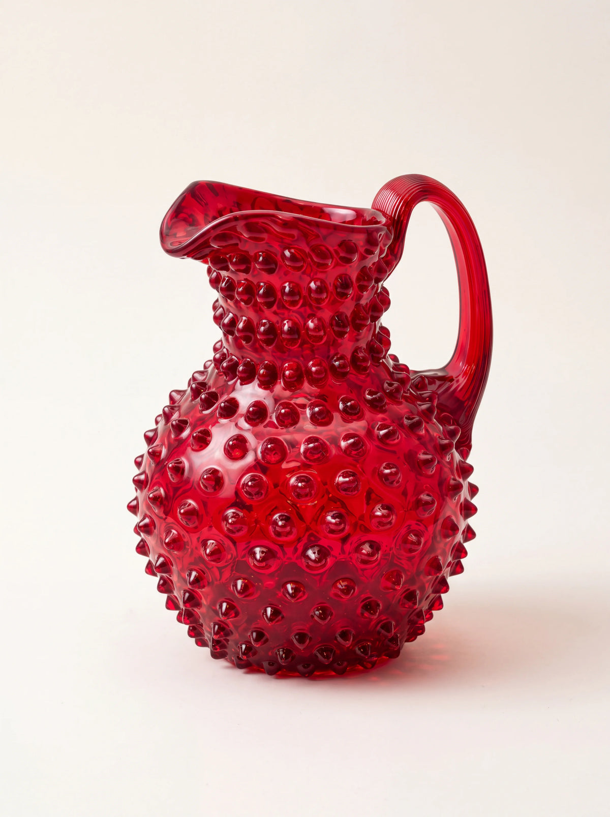 Garnet red hobnail glass jug with a rounded body, curved handle and integrated pouring spout