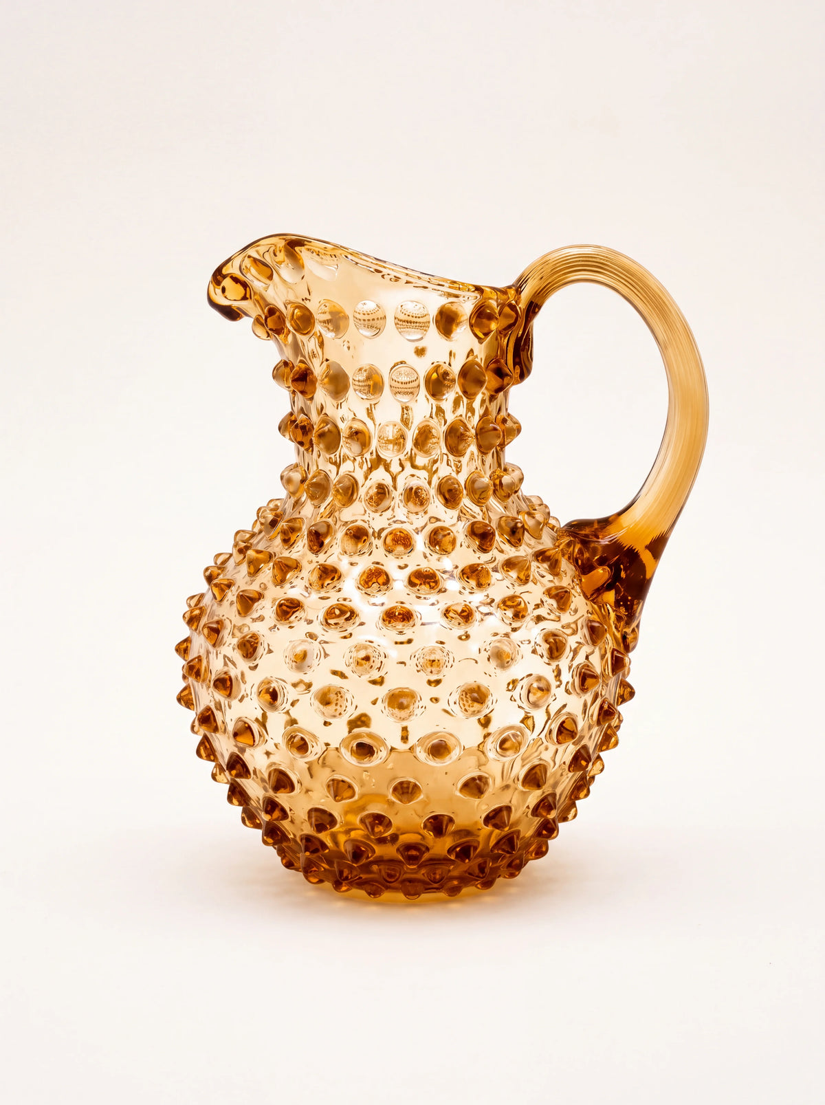 Gold topaz hobnail glass jug with a bulbous body, arched handle and pouring spout