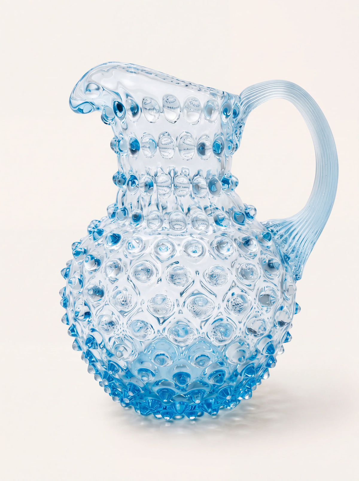 Light aquamarine hobnail glass jug with a rounded body, curved ribbed handle and pouring spout