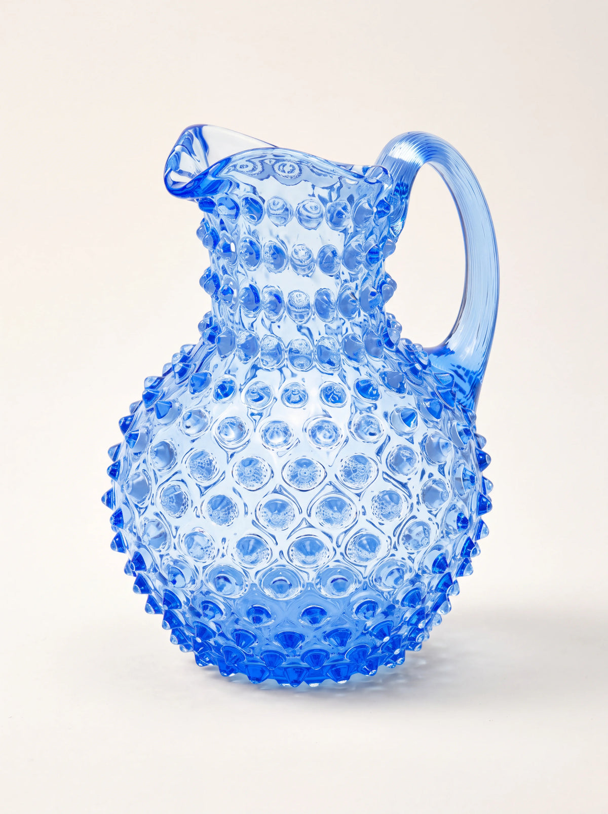 Light blue glass jug with a bulbous body, raised hobnail pattern, spout and curved handle