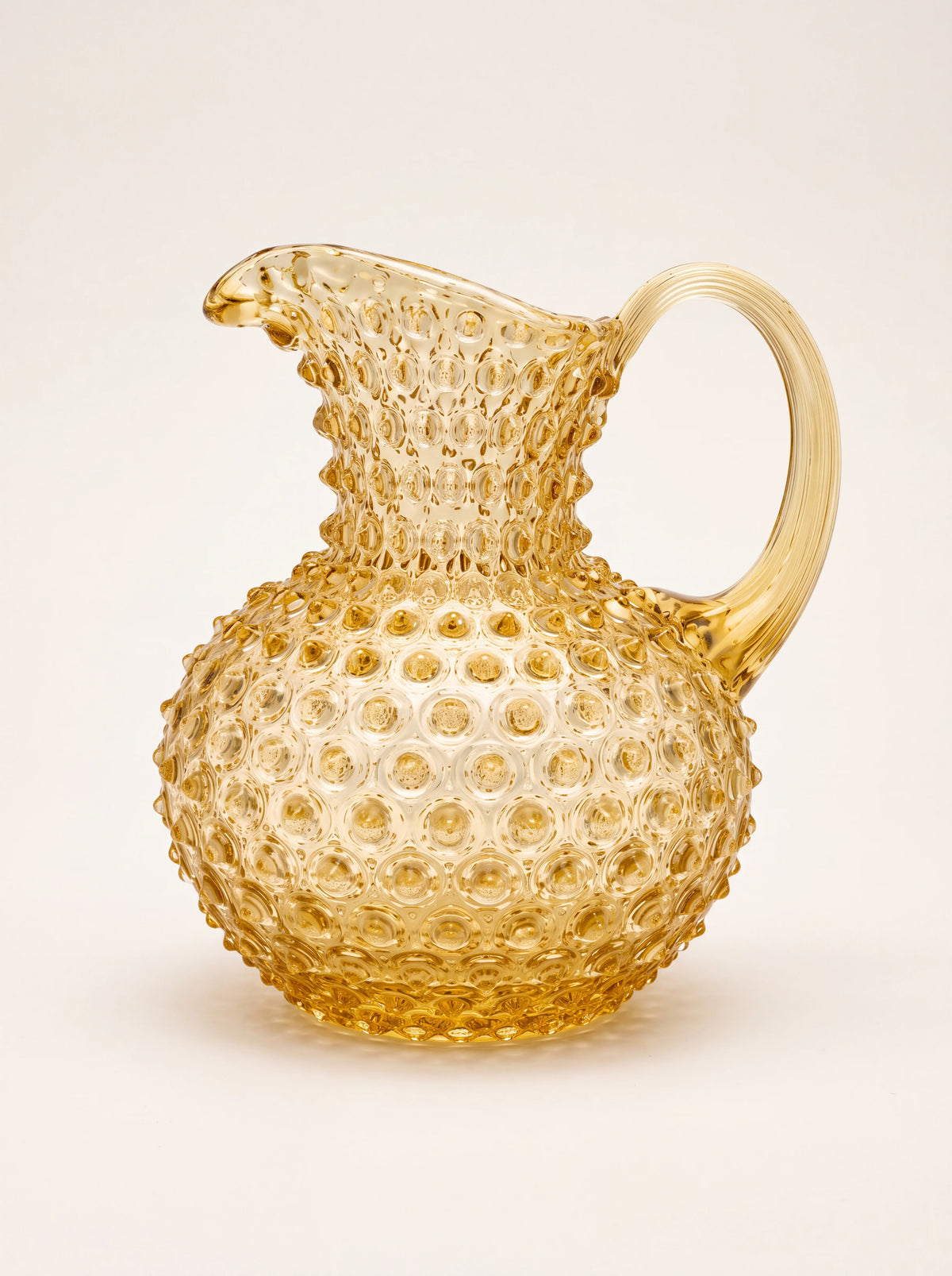 Amber hobnail glass jug with a rounded body, pouring spout and ribbed handle