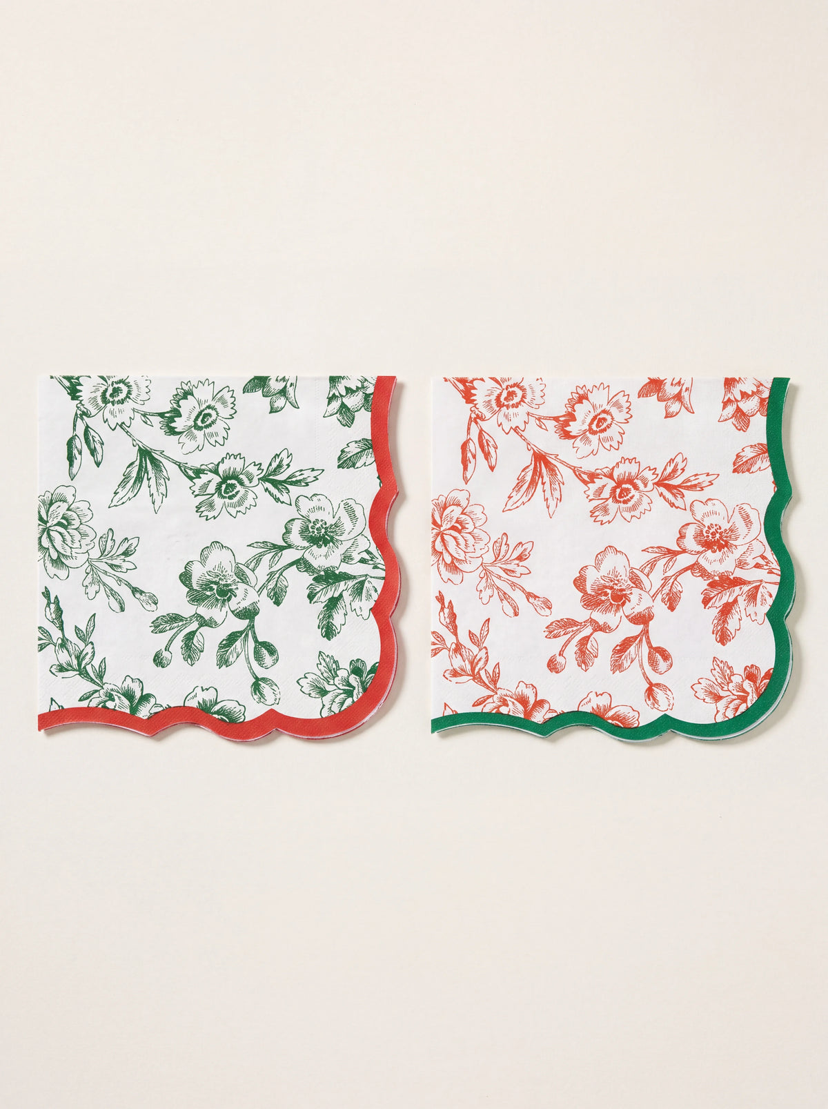 Scalloped paper napkins in two designs: green floral print with red trim, and red floral print with green trim