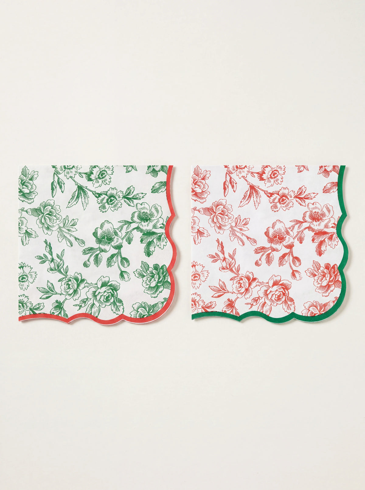 Folded square paper napkins showing the botanical floral pattern with wavy red and green scalloped edges