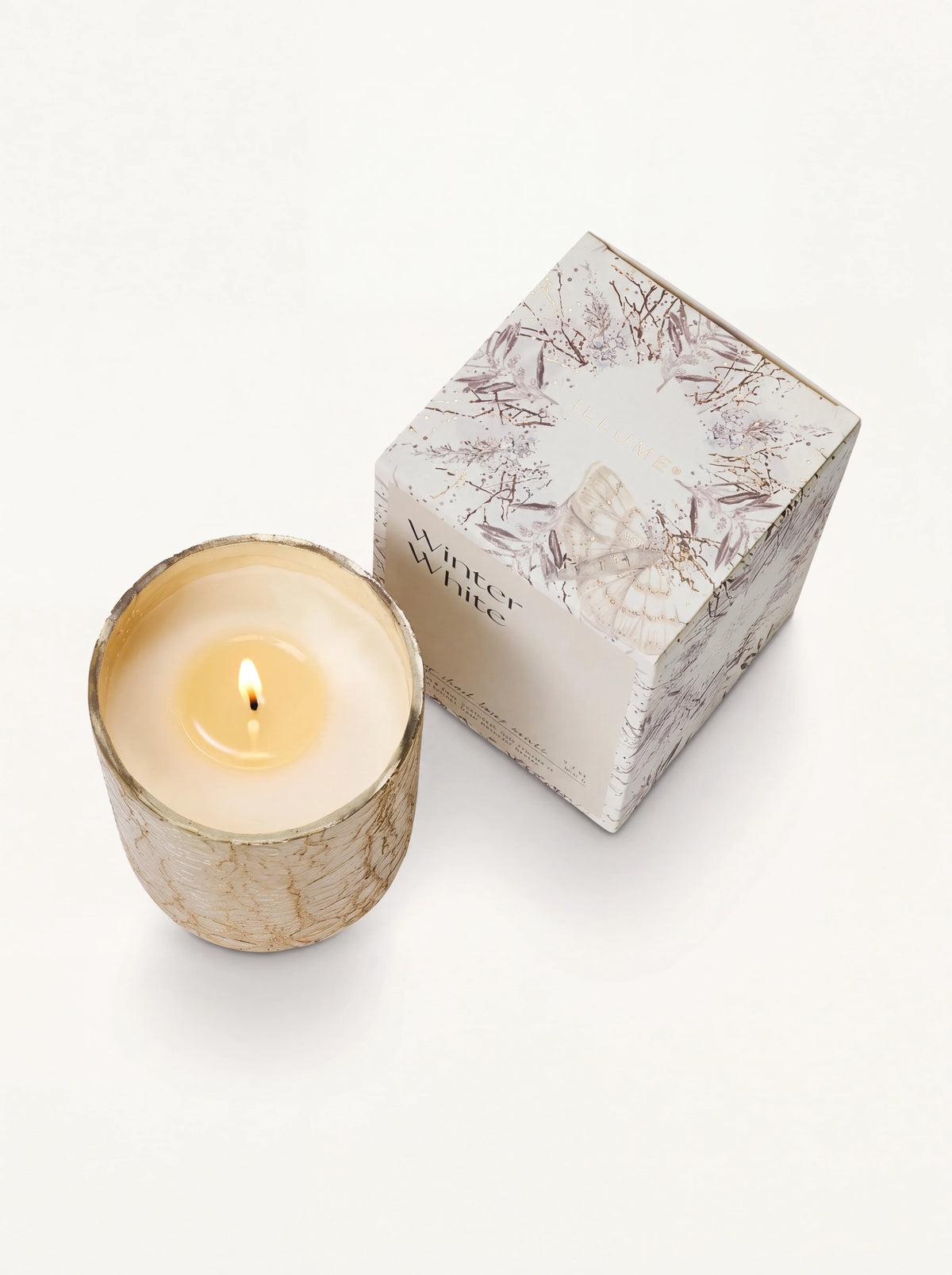 Top-down view of the lit candle with a burning wick beside its box marked Winter White