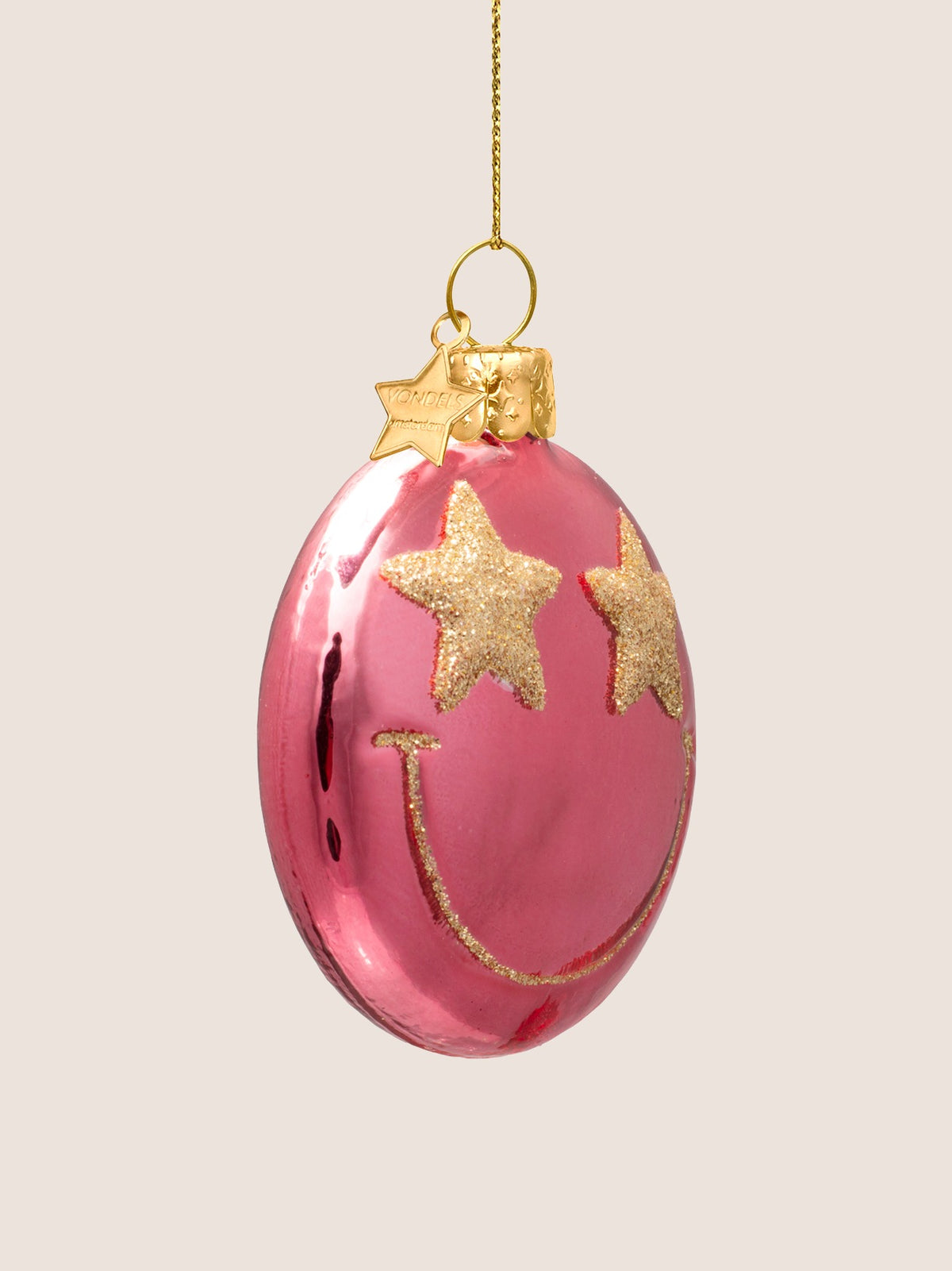 Three-quarter view showing the flattened disc profile of the pink glass smiley ornament