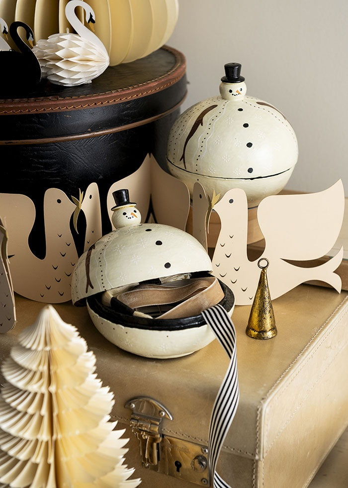 Snowman papier-mâché box shown open with ribbons inside, displayed among paper decorations