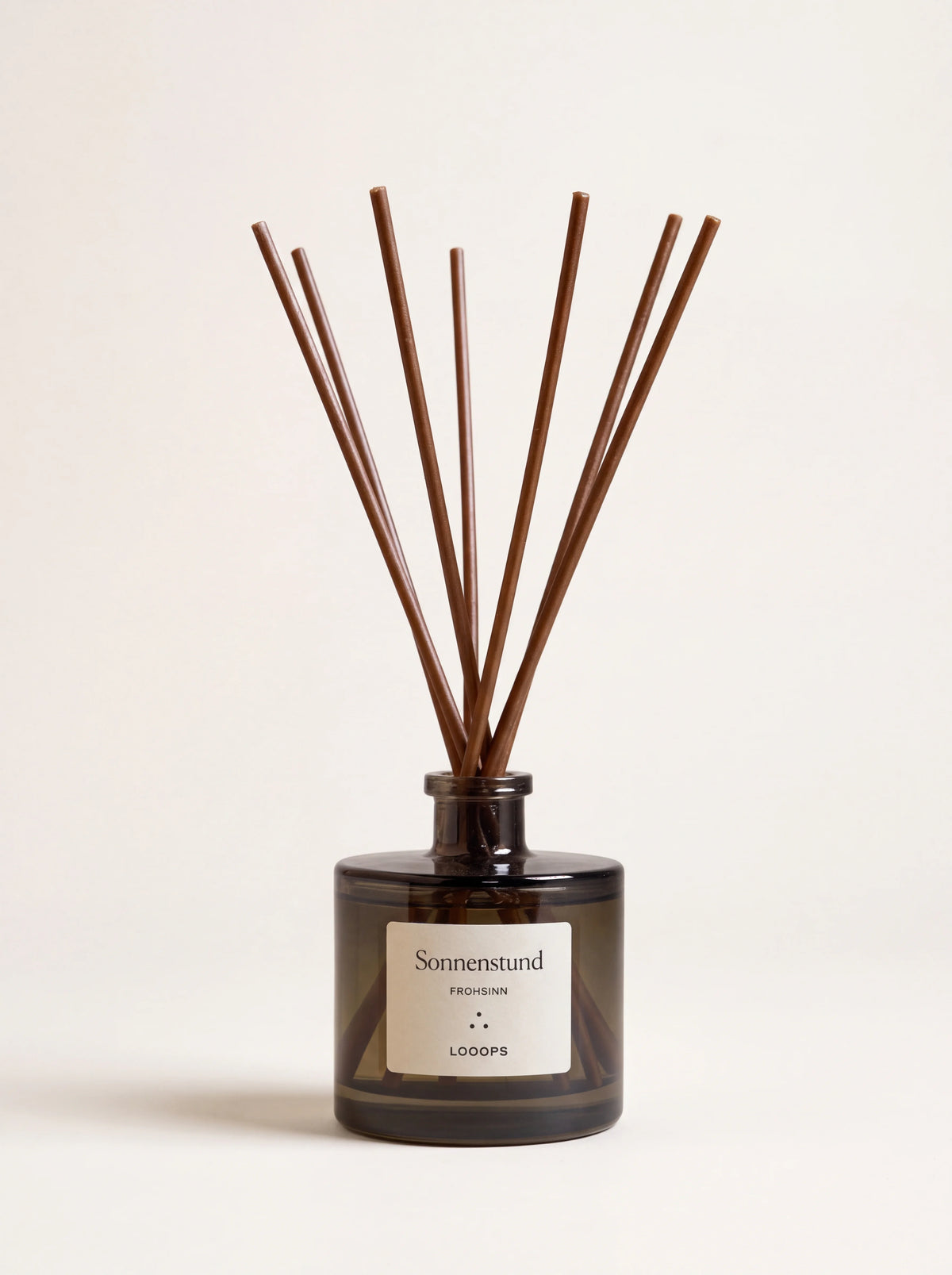 Cylindrical smoked glass reed diffuser with brown paper reeds and label reading Sonnenstund
