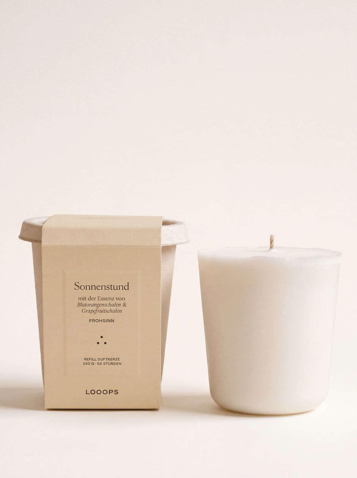 White vegetable wax candle refill standing next to its compostable cup packaging labelled Sonnenstund