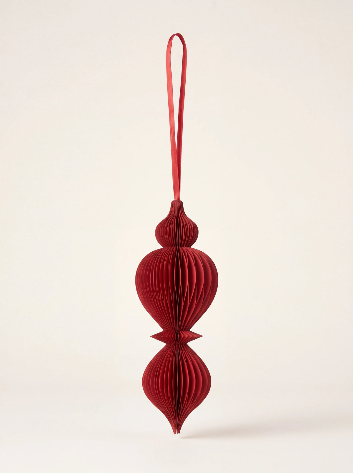 Spire honeycomb paper ornament in ruby red with a matching hanging ribbon loop