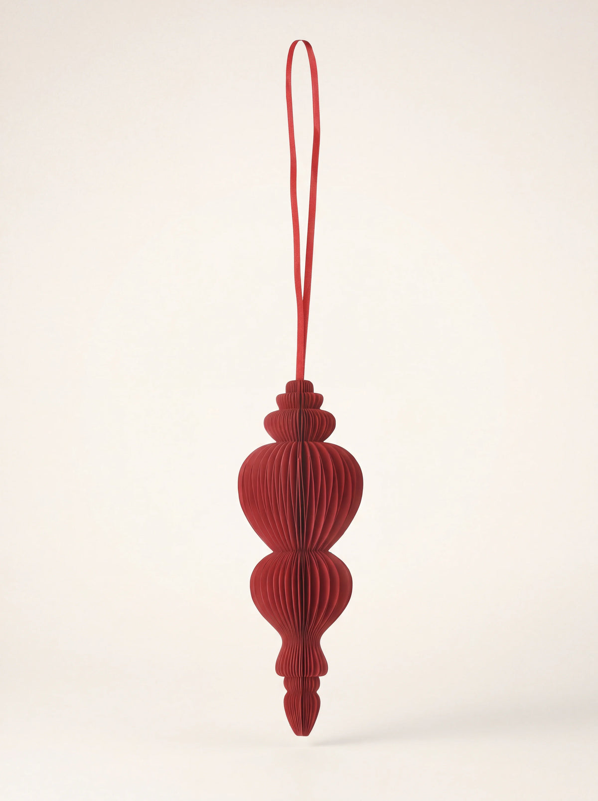 Ruby red paper spire ornament with a pleated honeycomb structure and matching hanging ribbon