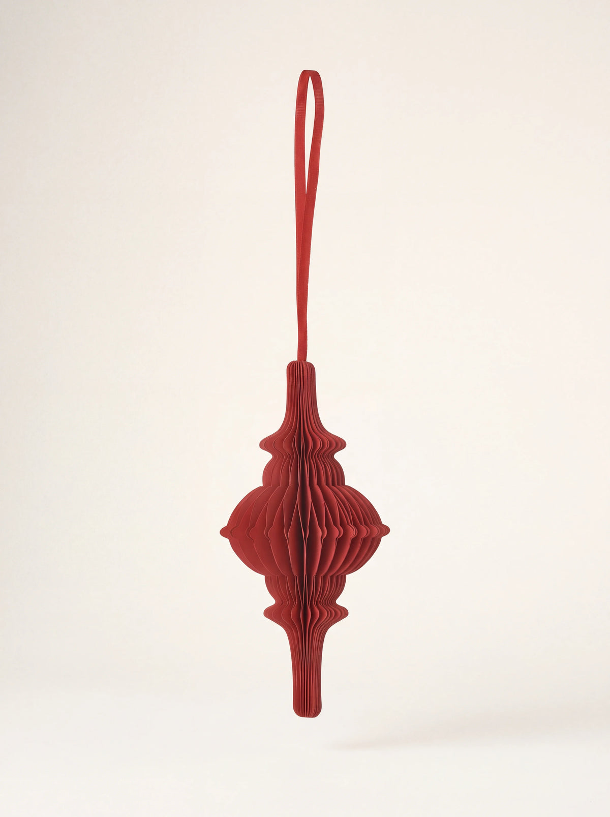 Ruby red spire-shaped paper ornament with honeycomb folds and a hanging ribbon loop